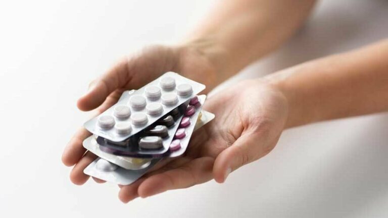 Hände halten mehrere Blisterverpackungen mit unterschiedlichen Tabletten in verschiedenen Farben.