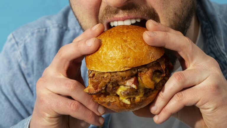 Eine Person hält einen saftigen Burger mit einem goldenen Brötchen und beabsichtigt, ihn zu essen.
