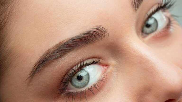 Naheaufnahme eines Gesichts mit betonten Augenbrauen und strahlend blauen Augen.