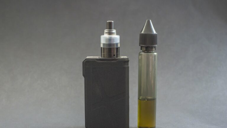 Ein Verdampfergerät links, daneben eine Flasche mit E-Liquid in einer transparenten Verpackung.